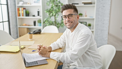 Handsome young hispanic man, confidently reading business documents with a successful smile,...