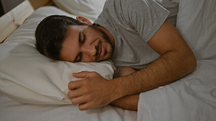 Hispanic young man sleeping peacefully in a comfortable bed indoors.