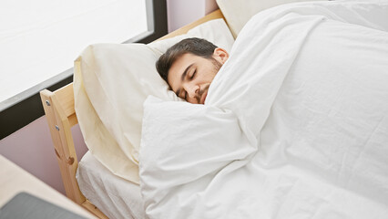 A peaceful hispanic man sleeps soundly in a bright bedroom with white bedding, embodying tranquility and rest.