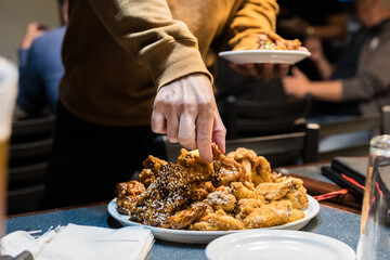 Delicious buffalo chicken wings at the bar. Hand holding a plate of buffalo wings at the local pub