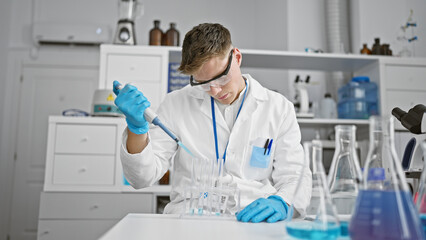 Handsome young caucasian scientist man, meticulously pouring liquid into test tubes in a high-tech...