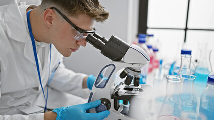 Handsome young caucasian man, a dedicated scientist, deeply engrossed in analyzing samples under...