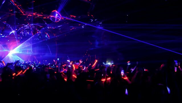audience hands up at a concert illuminated by laser light