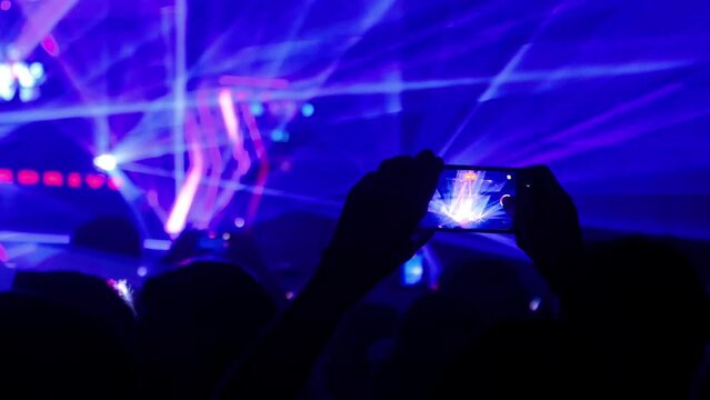 Hands holding mobile phone recording a music festival