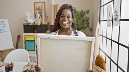 Confident african american woman artist smiling, looking at her beautiful drawing in art studio