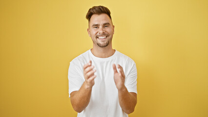Smiling bearded young man clapping hands against a vibrant yellow background.