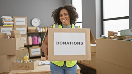African american woman with braids holding donation box in warehouse