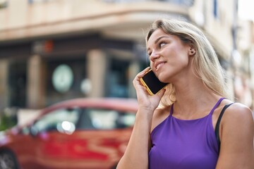 Fototapeta premium Young blonde woman smiling confident talking on the smartphone at street