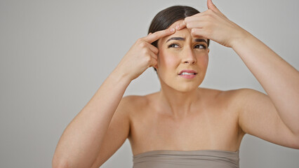 Young beautiful hispanic woman popping pimple over isolated white background