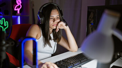 Young beautiful hispanic woman streamer tired using computer at gaming room