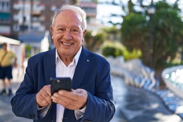 Middle age grey-haired man smiling confident using smartphone at park