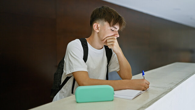 A thoughtful young man studying with a notebook at a university library, exuding focus and determination.