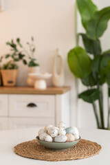 Painted Easter eggs in a plate on a white table. Kitchen background