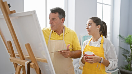 Man and woman artists seriously engrossed in drawing, sipping coffee together inside vibrant art...