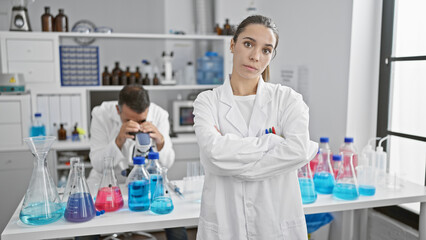 Two determined scientists, a man and woman, work together in a lab, portraying serious...