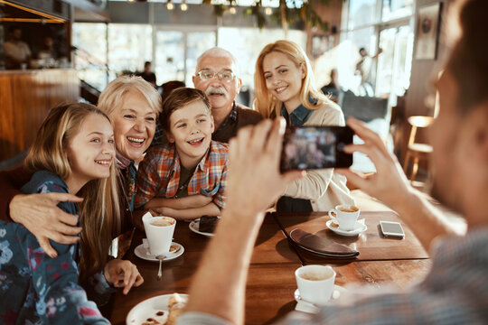 Multigenerational family taking a picture while having coffee and cake in a cafe