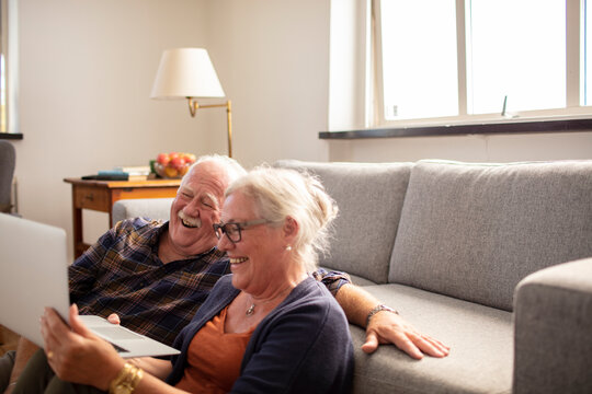 senior couple using a laptop at home in the living room - Powered by Adobe