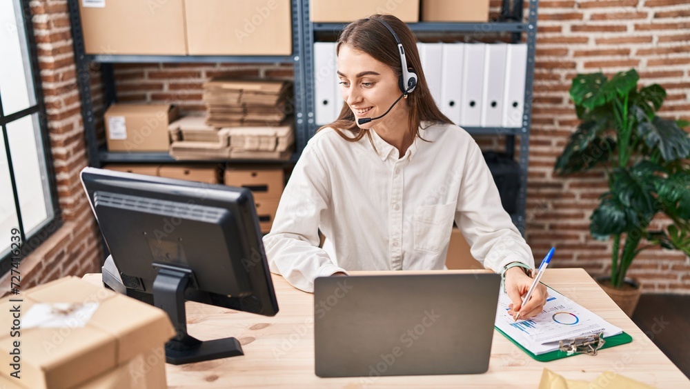 Wall mural Young caucasian woman ecommerce business worker having video call writing on document at office