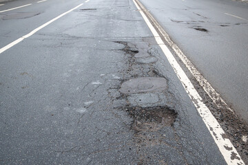 Broken asphalt road in city and untimely repair. Pothole asphalt with road markings. Roadway in bad...