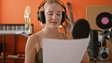 Young blonde woman musician smiling confident singing song at music studio