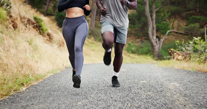 People, running and legs on mountain road or exercise, healthy and nature for marathon training or practice. Athlete, feet and race on forest hill or together as wellness goals, cardio or sport