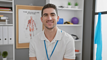 A smiling young hispanic man in a medical clinic's rehabilitation room, portraying a professional yet relaxed atmosphere.