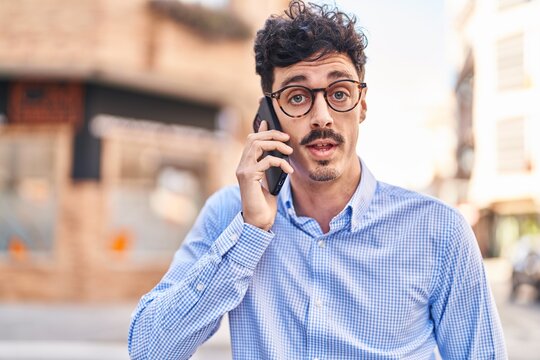 Young caucasian man talking on the smartphone with serious expression at street