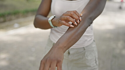 African american woman scratching arm for itchy at park
