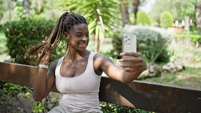 African american woman make selfie by smartphone sitting on bench at park