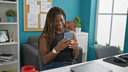 African american woman business worker using smartphone smiling at the office - Powered by Adobe