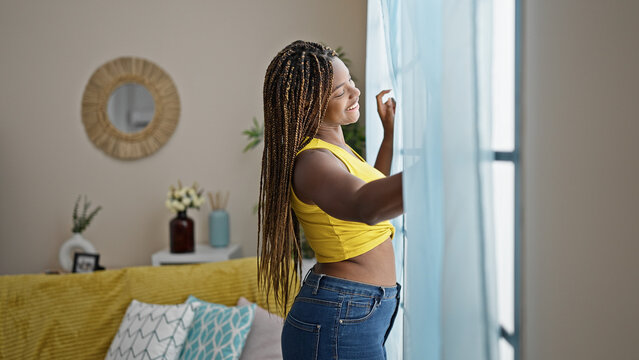 African american woman looking throw the window smiling at home