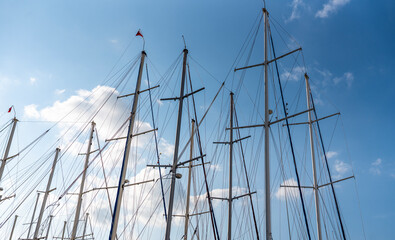The mast of a sailing ship against a clear blue sky. Ropes, rope ladders and other gear are visible.