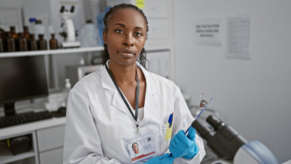 African american scientist woman with id card holding syringe in laboratory