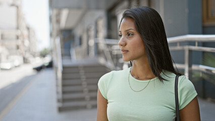 Young latin woman looking to the side with serious expression at street