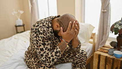 A bearded african american man in a leopard shirt feeling stressed in a bedroom with blurred decor in the background