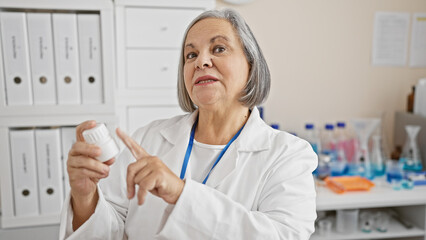 Mature woman pharmacist examines medication in a white lab, portraying healthcare professionalism indoors.