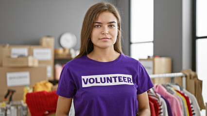 Young beautiful hispanic woman volunteer standing with serious face at charity center