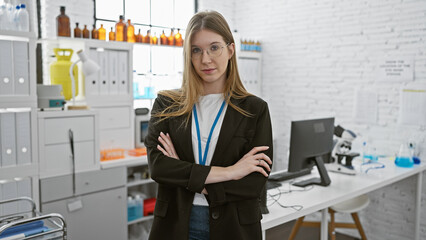 Caucasian woman with crossed arms in a laboratory setting, looking professional and attentive...