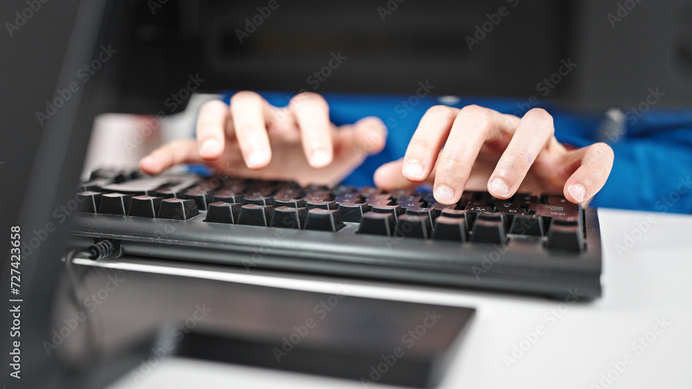 Wall mural Young hispanic man using computer typing on keyboard at the office