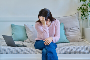 Unhappy mature woman experiencing headaches stress depression sitting on couch at home