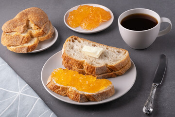 Sandwiches with apricot jam and a cup of coffee on a gray background. Breakfast concept