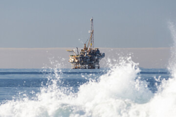 An Old Oil Rig In the Distance Beyond Crashing Waves