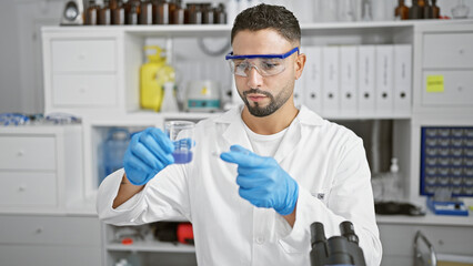 A bearded man in lab coat examines a test tube in a modern laboratory, showcasing a professional...