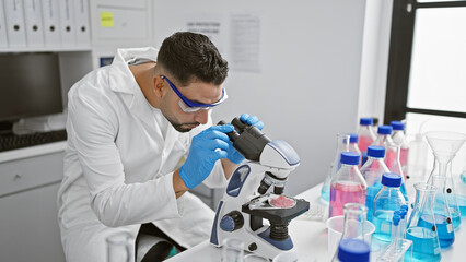 A focused man examining samples under a microscope in a modern laboratory setting, representing research and medical expertise.