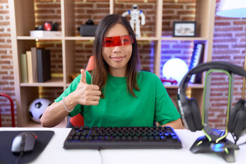 Fototapeta na wymiar Middle age chinese woman wearing virtual reality glasses doing happy thumbs up gesture with hand. approving expression looking at the camera showing success.