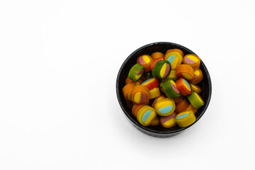 Multicolored gummy candy in a bowl on a white background