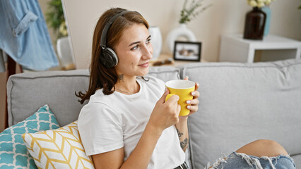 Young woman listening to music smelling coffee at home