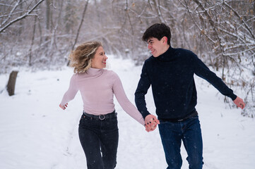 A young couple walks in the park in winter without jackets. 