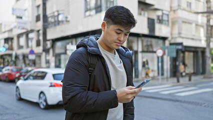 Handsome asian man using smartphone on a bustling city street, portraying urban lifestyle and...