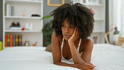 African american woman lying on bed looking sexy with serious face at bedroom